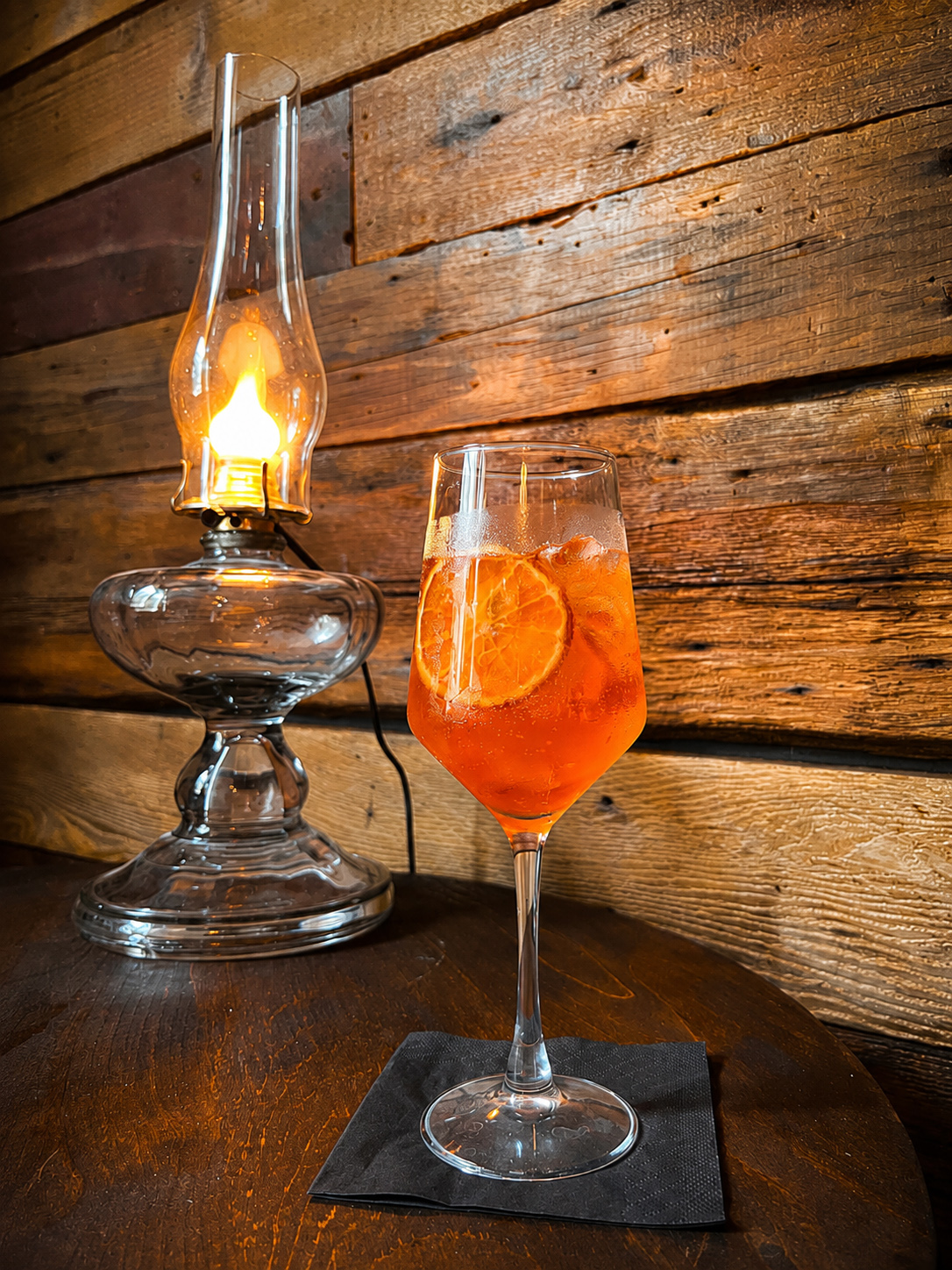 orange spritz cocktail beside a glowing lantern at Sugar Hollow Crossing